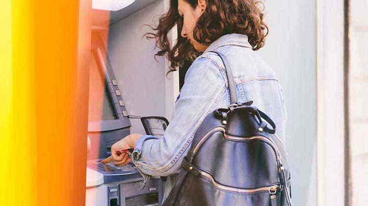 一名妇女使用自动柜员机轻松提取支票账户资金.