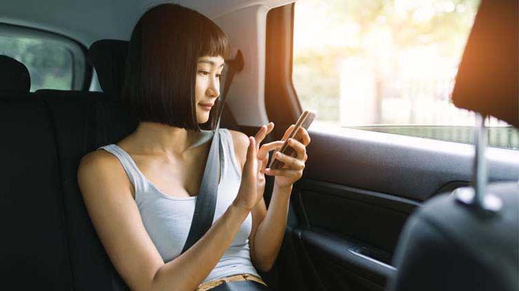一个女人坐在车里用手机的画面.