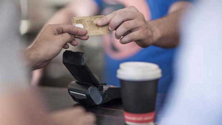 A teenager hands over a credit card as a payment for coffee.