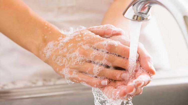 在流动的水龙头下用肥皂泡洗手的人.