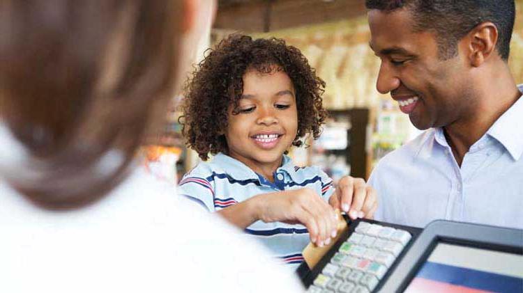 一位父亲让他年幼的儿子拿着他的信用卡在商店收银台刷卡.