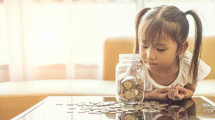年轻的女孩在看一罐硬币.