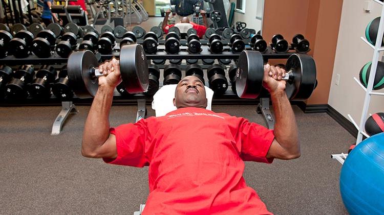 利用公司的福利，一名男子在健身房举重.