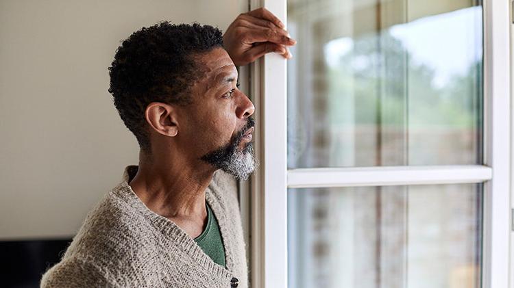 Man looking out the window considering post divorce finances.